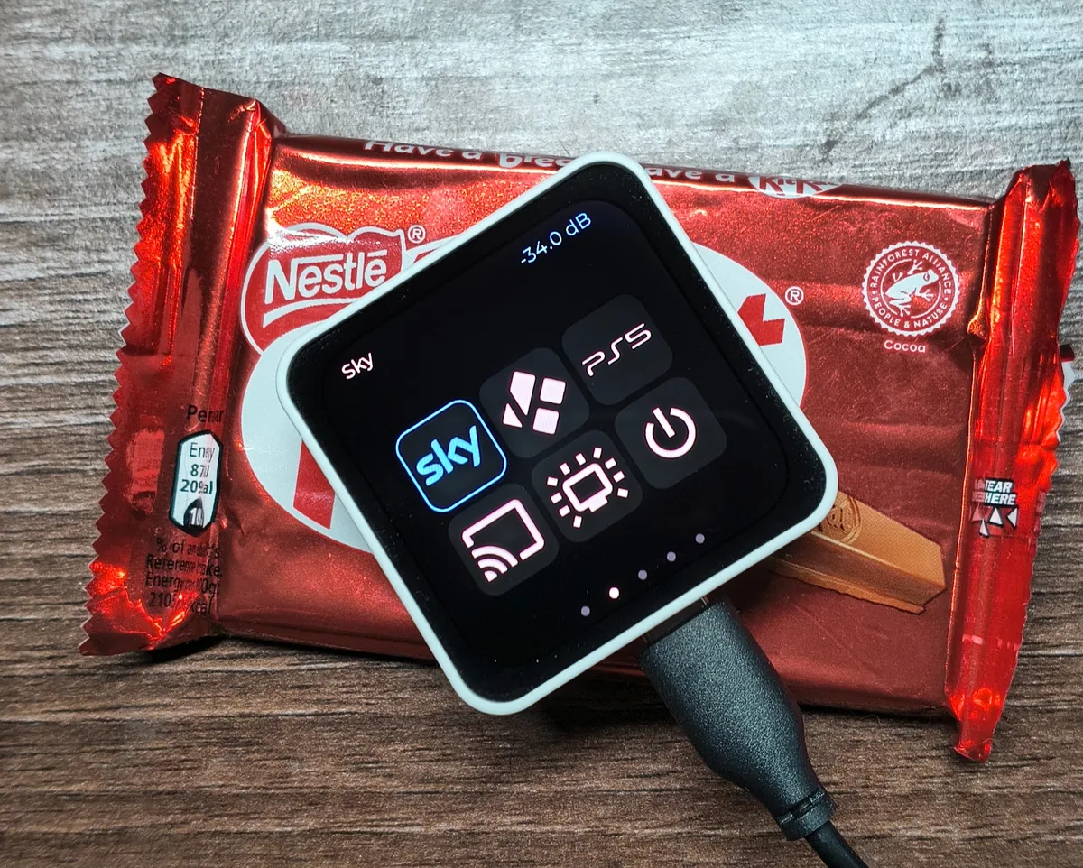The remote on its side on a chocolate bar, showing the Activities page: Sky highlighted, Kodi, PS5, Chromecast, TV and power tiles